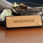 Reserviertschild aus Leder Holz Erle Schild für Tischreservierung im Restaurant aus Leder mit Holz und mit Dekoration im Hintergrund.